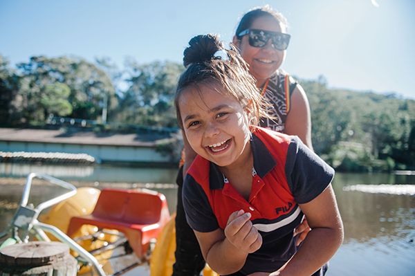 A mother and daughter laughing and smiling happy next to a swimming area