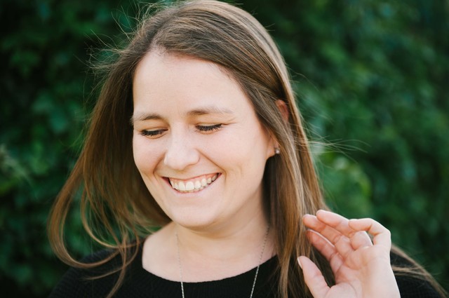 An adult female smiling with her eyes closed