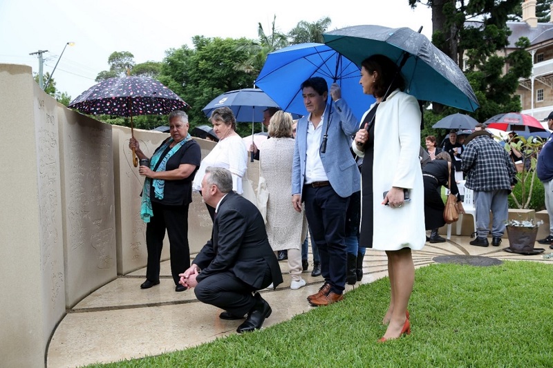 Group of people standing with umbrellas at memorial wall